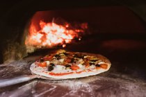 Close up of pizza in a wood-fired oven in a restaurant. — Stock Photo