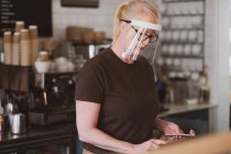 Garçonete loira usando máscara facial trabalhando em um café. — Fotografia de Stock
