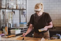 Camarera rubia con máscara facial trabajando en un café, preparando comida. - foto de stock