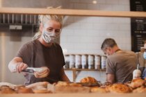 Cameriera bionda con la maschera facciale che lavora in un caffè. — Foto stock