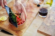 Нарезанный базилик добавляется в томатный салат, обрезанный кадр — стоковое фото