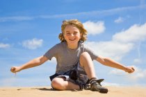 Boy (9yrs old) sitting on sand dune in South Wales, United Kingdom — Stock Photo