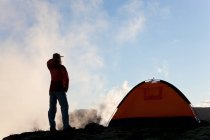 Woman standing by tent at sunrise, Iceland — Stock Photo