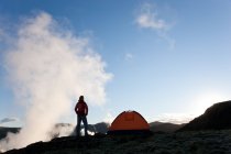 Femme debout près de la tente au lever du soleil, Islande — Photo de stock