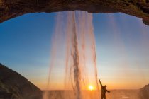Hombre detrás de Seljalandsfoss Waterfall, Islandia del Sur, Islandia - foto de stock