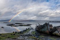 Arcobaleno e vecchie barche da pesca in legno spiaggiate sulla riva a Salen — Foto stock