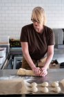 Donna in grembiule marrone in piedi in una cucina caffè, mescolando cottura pasta pasticceria danese — Foto stock