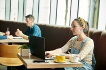 Жінка сидить у кафе за допомогою ноутбука — стокове фото