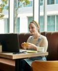 Жінка сидить у кафе, використовуючи ноутбук, що взаємодіє під час онлайн-дзвінка — стокове фото