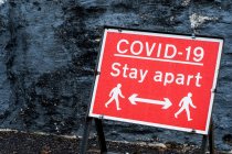 Primo piano del cartello di distanza Covid-19 rosso e bianco. — Foto stock