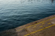 Ângulo alto perto de pegadas amarelas e linhas pintadas no solo asfáltico em um porto. — Fotografia de Stock