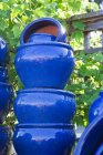 Ollas azules pintadas apiladas en el centro del jardín. - foto de stock
