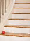 Escalera de madera con barandilla y manzana roja. - foto de stock