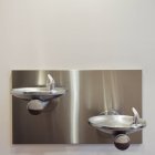 Два металлических питьевых фонтана, установленных на стене на разных высотах. — стоковое фото
