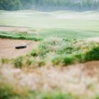 Rake in sand bunker on misty golf course. — Stock Photo