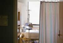 Krankenhauszimmer mit Bett und Vorhang zur Privatsphäre. — Stockfoto