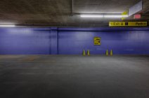 Parcheggio sotterraneo con coni di traffico e muro blu. — Foto stock