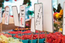 Signos y productos orgánicos en el puesto de verduras en el mercado - foto de stock