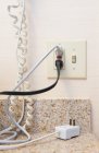 Cords plugged into electrical socket or outlet and telephone cable. — Stock Photo