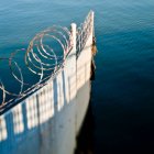 Гофрированный железный забор и колючая проволока в океане — стоковое фото