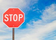 Red stop sign by the side of a road — Stock Photo