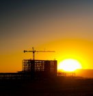 Puesta de sol detrás de la construcción de edificios de gran altura y grúas. - foto de stock