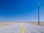Highway disappearing to vanishing point in rural landscape. — Stock Photo