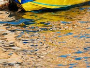 Barco amarelo atracado com reflexos na água. — Fotografia de Stock