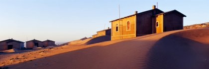 Case sepolte nella sabbia in un villaggio deserto. — Foto stock
