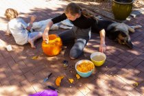 Teenage girl and her younger brother carving pumpkins on patio. — Stock Photo