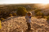 Young boy in Galisteo Basin looking through binoculars at sunset — Stock Photo