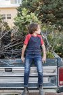 Jeune garçon assis sur une vieille camionnette pleine de broussailles — Photo de stock