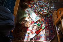 Хлопчик сидить серед іграшок на підлозі своєї спальні на плямі сонячного світла — стокове фото