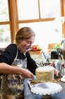 Дівчина-підліток на кухні, застосовуючи глазур до торта — стокове фото