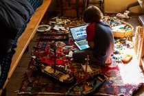 Jeune garçon jouant dans sa chambre, regardant ordinateur portable — Photo de stock