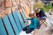 Девочка-подросток и ее мать красили деревянные полки в синий цвет на террасе — стоковое фото