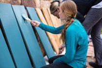 Adolescente et sa mère peignent des étagères en bois bleues sur une terrasse — Photo de stock