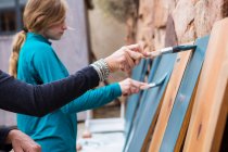 Ragazza adolescente e sua madre dipingere scaffali di legno blu su una terrazza — Foto stock