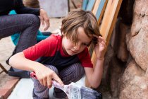 Семилетний мальчик с помощью кисти и картона — стоковое фото