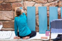Дівчина-підліток малює дерев'яні полиці синій . — стокове фото