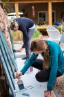 Дівчинка-підліток і її мати малюють дерев'яні полиці синіми на терасі — стокове фото