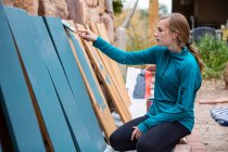 Дівчина-підліток малює дерев'яні полиці синій . — стокове фото