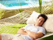 Giovane uomo che dorme su un'amaca vicino a una piscina — Foto stock