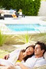 Joyeux jeune couple à la maison relaxant, partageant un hamac — Photo de stock