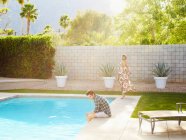 Jovem e mulher passando tempo à beira de uma piscina — Fotografia de Stock
