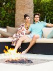 Feliz jovem casal em casa, sentado ao lado de um firepit ao ar livre — Fotografia de Stock