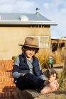 Портрет молодого хлопчика в капелюсі, що розслабляється на ганку — стокове фото