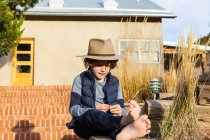 Ritratto di giovane ragazzo che indossa cappello fedora rilassante sul suo portico — Foto stock