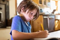 Jeune garçon à la maison écriture et dessin dans son tampon de dessin — Photo de stock