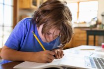 Junge zu Hause schreibt und zeichnet im Zeichenblock — Stockfoto